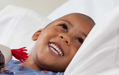 A boy smiling in a hospital bed.