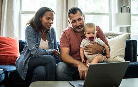 Couple holding baby and looking at computer