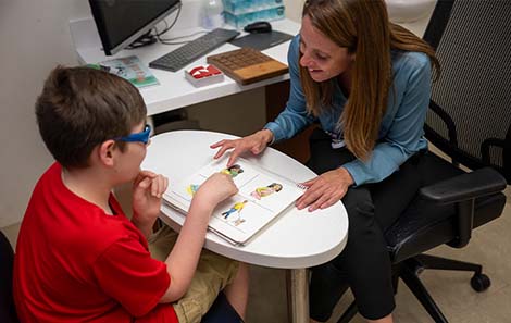 pediatric neuropsychologist and patient sit together at table and use images to communicate