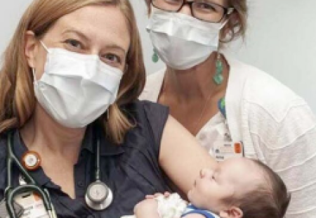 Two doctors hold up baby born with SMA